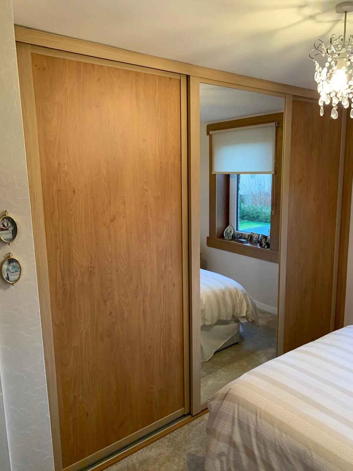 Fitted oak-effect sliding wardrobe with mirrored door in an East Lothian bedroom