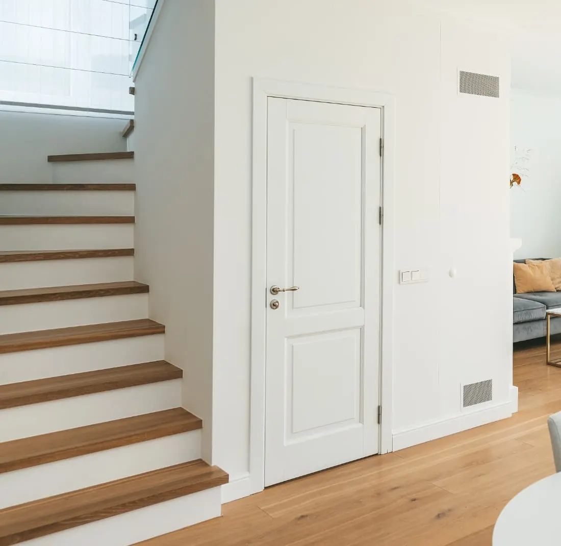 White panelled internal door beside an oak and white staircase